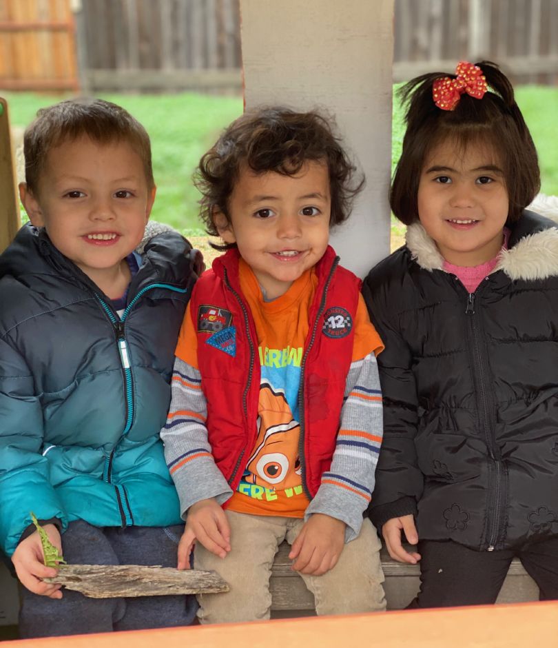 3 kids sitting and smiling for camera.