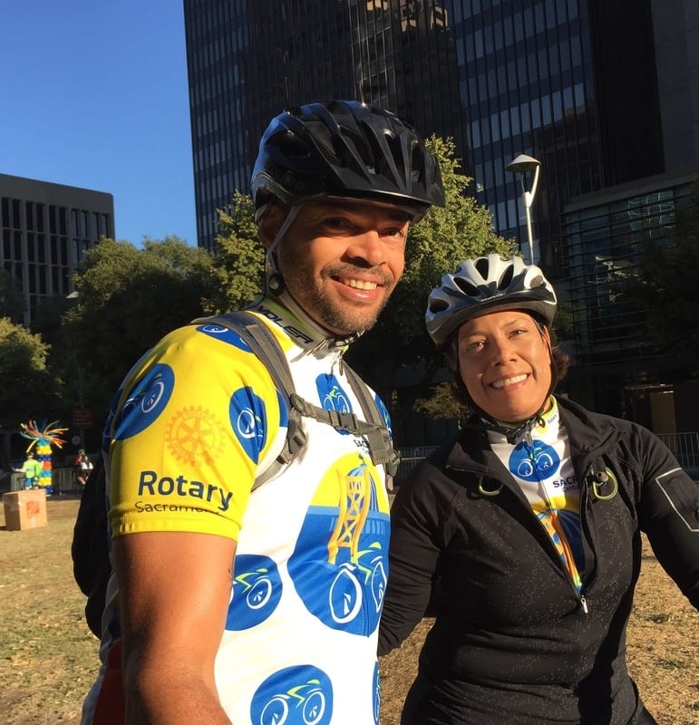 A participant with Sacramento Century Challenge jersey taking picture with a participant with a suit.