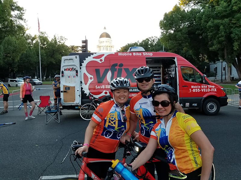 Three participants taking picture in front of the Velofix car